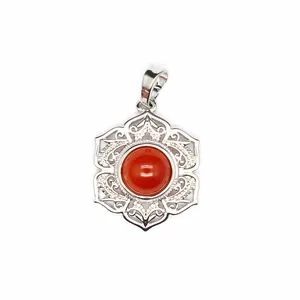Détail d'un pendentif vintage argenté avec une pierre rouge ronde et des pétales filigranés.