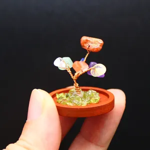 Detailed view of a miniature natural stone tree of life held by fingers to show small scale