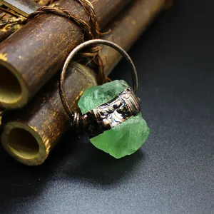 Close-up detail of a raw green crystal pendant with antique copper wire wrapping