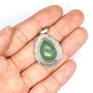 Close-up of teardrop green stone pendant with ornate silver filigree border