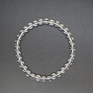 Close-up of 6mm clear quartz crystal round bead bracelet for women on gray background