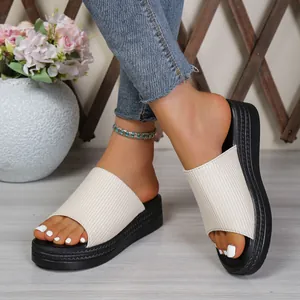 Close-up of women's off-white ribbed fabric platform slides worn with denim jeans