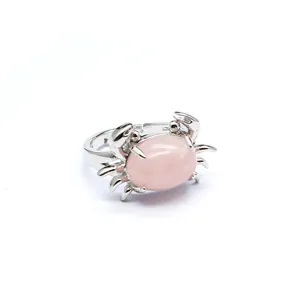 Detailaufnahme eines silbernen Krabbenrings mit einem glatten, ovalen rosa Stein