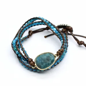 Close-up of handmade natural stone wrap bracelet with blue beads and oval centerpiece.