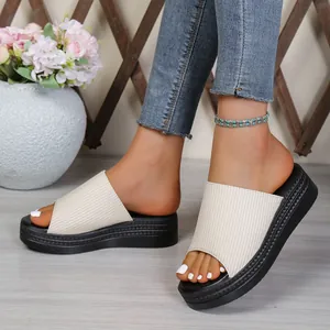 Macro detail of women's cream ribbed fabric platform slides with thick black soles.