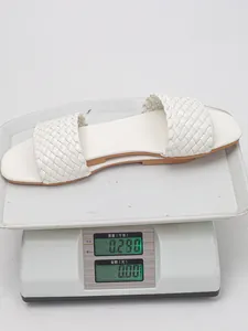 Weight measurement of white braided flat sandal on a scale showing approximately 0.28kg