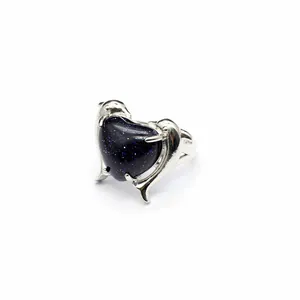 Primo piano di un anello a doppio delfino argentato con un cuore in pietra blu