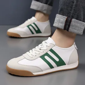 Detailed view of white men's sneakers with green stripes and tan gum soles