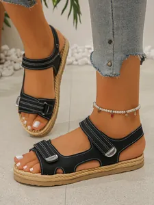 Dettaglio di sandali neri con zeppa, cinturini in velcro e suola in corda intrecciata