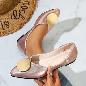 Detalle de zapatos planos puntiagudos rosa metalizado con hebilla dorada circular.