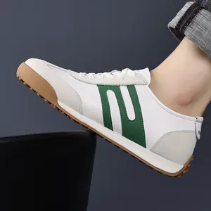 Side view detail of stylish white men's sneakers with green stripes and classic gum sole