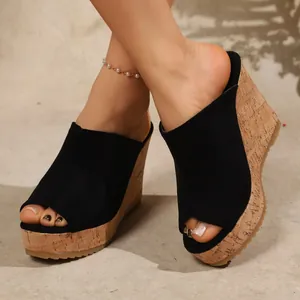 Close-up detail of women's black suede peep-toe wedge platform sandals on feet