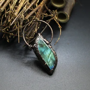 Close-up of raw labradorite crystal pendant with blue-green flashes and rustic copper frame