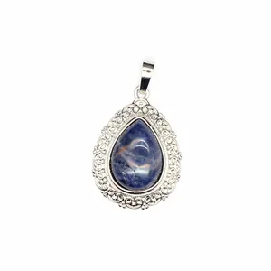 Detail of a teardrop natural stone pendant with ornate silver filigree border