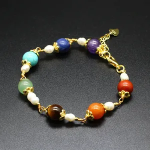 Detail view of handmade chakra stone bracelet with pearls and gold-plated wire wrapping