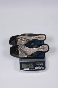 Báscula de precisión pesando elegantes sandalias de tacón negras con tiras de pedrería
