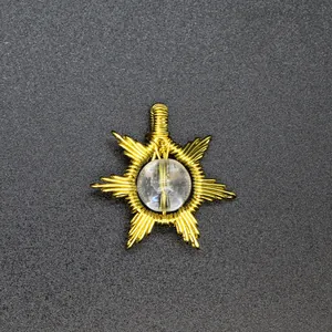 Detailed view of a hand-woven gold wire sun pendant with a clear natural stone center