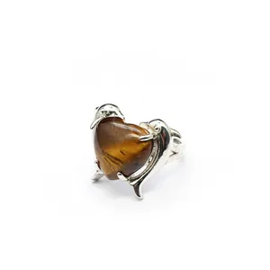 Vista macro di un anello in argento con pietra occhio di tigre a cuore e delfini