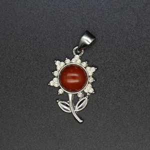 Detailaufnahme eines silbernen Blumenanhängers mit einem zentralen roten Jaspis