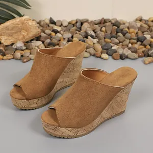 Detail view of brown suede peep-toe wedge sandals with cork texture heel.