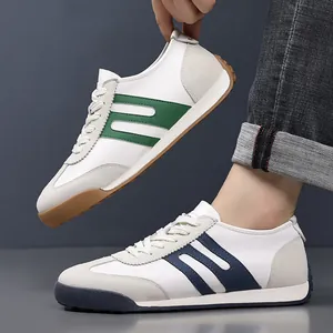 Detailed view of men's white leather sneakers with green and navy side stripes