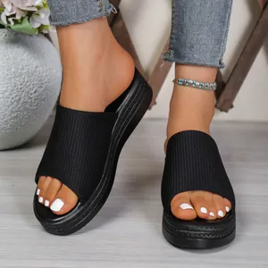 Close-up view of women's black ribbed fabric platform slide sandals worn for summer leisure