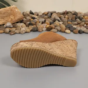 Detail view of the anti-slip rubber outsole and cork wedge on a tan suede platform sandal