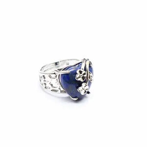 Detail view of a silver-tone open ring with a blue heart stone and floral accents