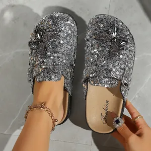 Detailed view of silver sequined clogs featuring black butterfly appliques.