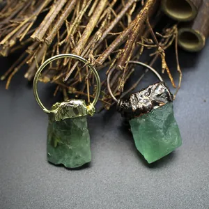 Detailed macro view of raw green crystal stone pendants with metallic caps.