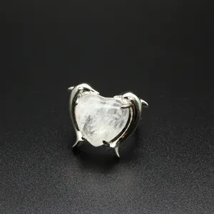 Vista macro di un anello a delfino d'argento con una pietra di cristallo naturale a cuore