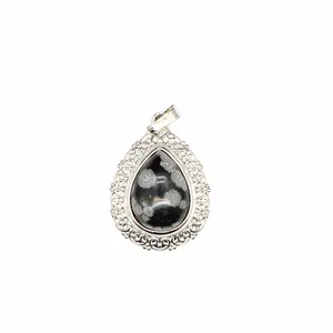 Macro shot of a teardrop natural stone pendant with elegant silver filigree border.