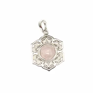 Gros plan d'un pendentif floral argenté avec un cristal rose rond au centre.