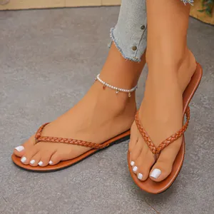 Close-up of stylish brown braided thong sandals worn on model's feet for beach.