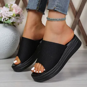 Close-up of women's black platform slides with ribbed fabric upper and textured sole