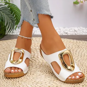 Close-up of white wedge slides featuring a stylish oversized gold buckle detail