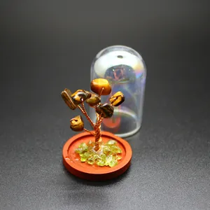 Close-up of mini crystal money tree with tiger eye stones and glass dome