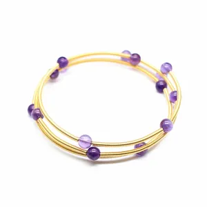 Détail d'un bracelet jonc doré à trois rangs avec des perles d'améthyste violettes