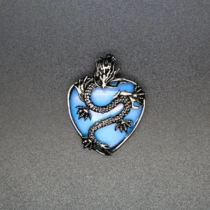Dettaglio di un drago d'argento avvolto attorno a un ciondolo a cuore blu.