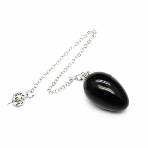 Macro view of a smooth black natural stone egg pendulum with silver chain and bead