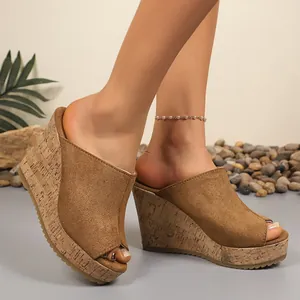 Detailed side view of brown suede peep-toe wedge sandals with cork soles