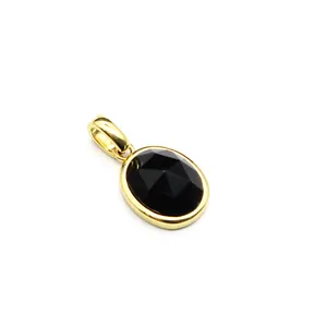 Detail view of an oval black faceted stone pendant with gold bezel and bail.