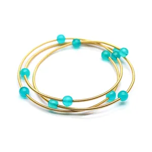 Gros plan d'un bracelet jonc à trois couches plaqué or 24 carats avec perles vertes