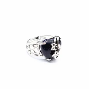 Close-up detail of a heart-shaped blue goldstone ring with silver flower accents
