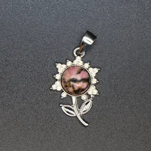 Nahaufnahme eines silbernen Blumenanhängers mit rosa Naturstein und glänzenden Kristallen