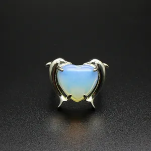 Dettaglio di un anello a doppio delfino regolabile con pietra opale a forma di cuore