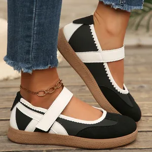 Primo piano di scarpe Mary Jane bianche e nere con cinturino a strappo e suola in gomma marrone.