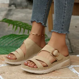 Detailed view of beige suede wedge sandals with buckle and thick platform sole.