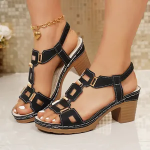 Dettaglio di sandali platform neri con tacco largo e accenti dorati alla moda.