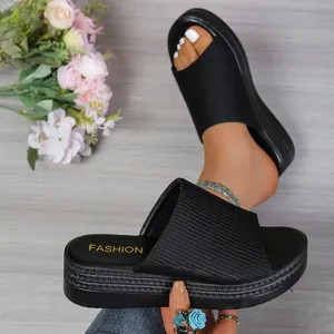 Close-up detail of women's black fabric platform slides with woven texture sole